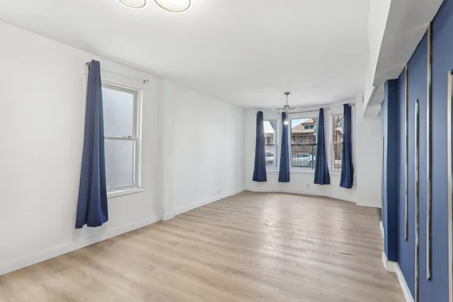 a view of an empty room with a window and wooden floor