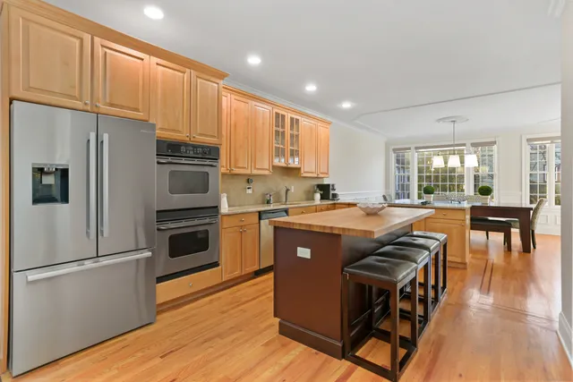a kitchen with stainless steel appliances granite countertop a refrigerator a stove top oven a sink dishwasher and white cabinets with wooden floor