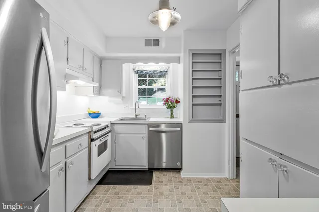 a kitchen with a sink cabinets stainless steel appliances and a window
