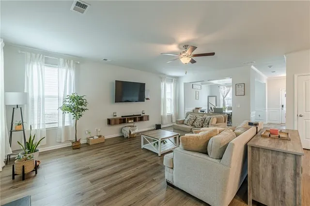 a living room with furniture a ceiling fan a flat screen tv and a window