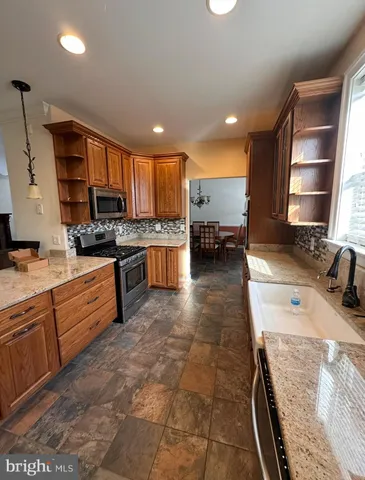 a view of a dining room and livingroom with furniture wooden floor a rug a painting and a chandelier