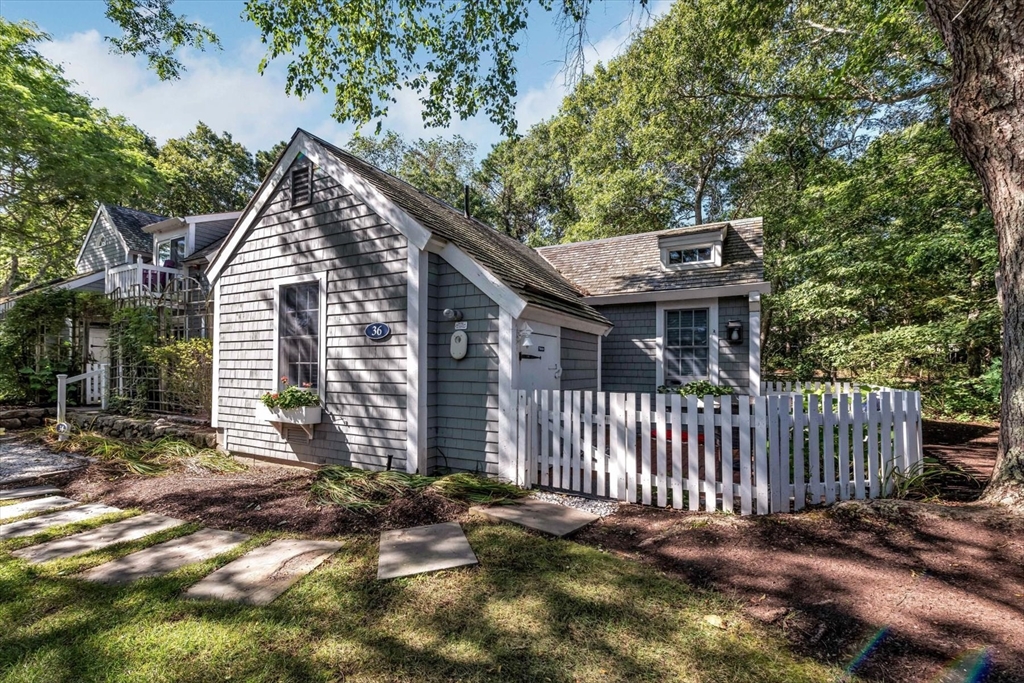 36 Brant Rock Road, Unit 821 Mashpee, MA 02649 - Photo 2 of 23 a view of a house with a small yard and wooden fence