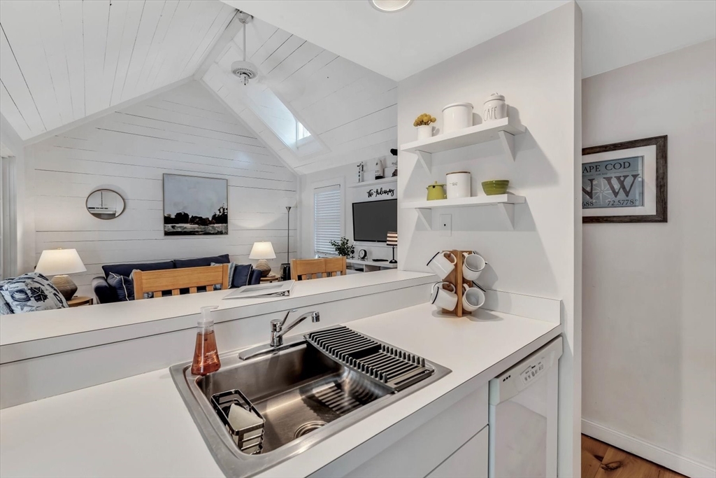 36 Brant Rock Road, Unit 821 Mashpee, MA 02649 - Photo 9 of 23 a kitchen with a sink dishwasher and a stove with white cabinets