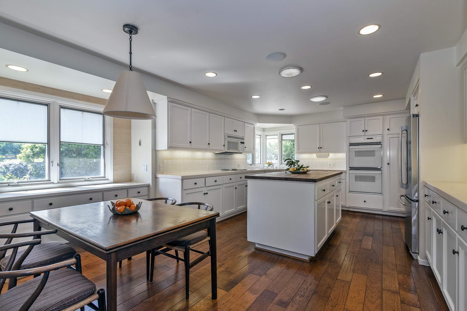 a kitchen with stainless steel appliances granite countertop a stove refrigerator a sink dishwasher a dining table and chairs with wooden floor