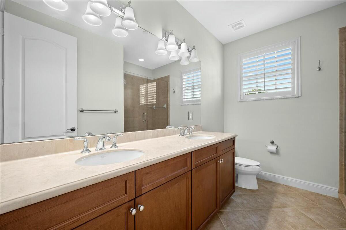222 Tresana Boulevard, Unit 44 Jupiter, FL 33478 - Photo 24 of 63 a bathroom with a granite countertop sink a toilet and a mirror