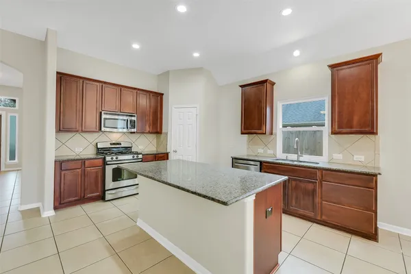 a kitchen with stainless steel appliances granite countertop a sink counter space cabinets and a large window
