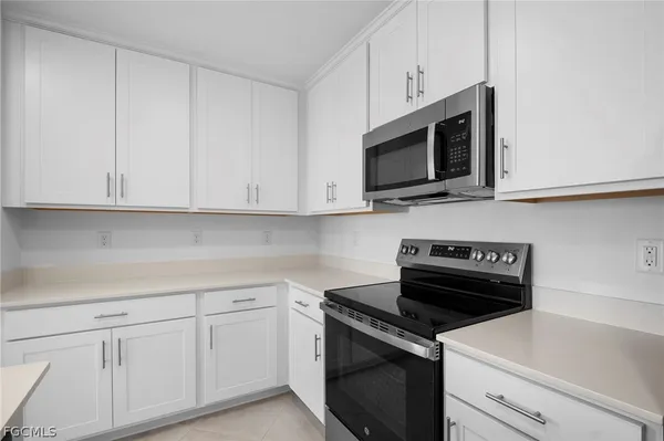 a kitchen with white cabinets and black appliances