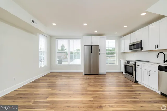 a view of kitchen with granite countertop cabinets and refrigerator