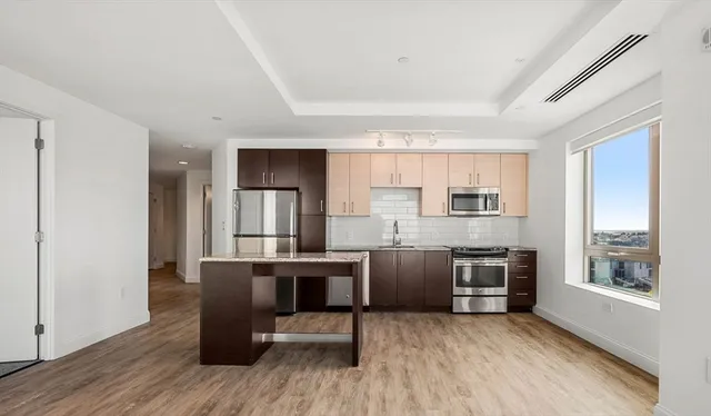 a view of kitchen with stainless steel appliances granite countertop a stove top oven a sink dishwasher a dining table and chairs with wooden floor