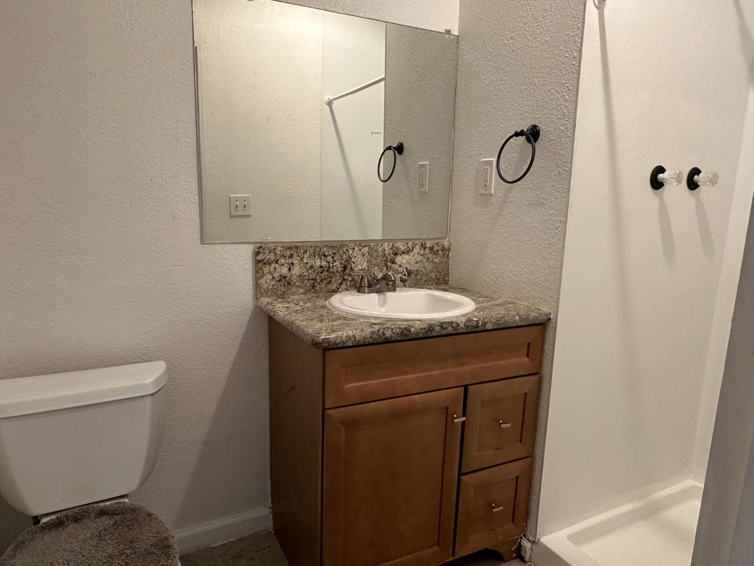 1235 N Street Newman, CA 95360 - Photo 12 of 33 a bathroom with a granite countertop sink a toilet and a mirror