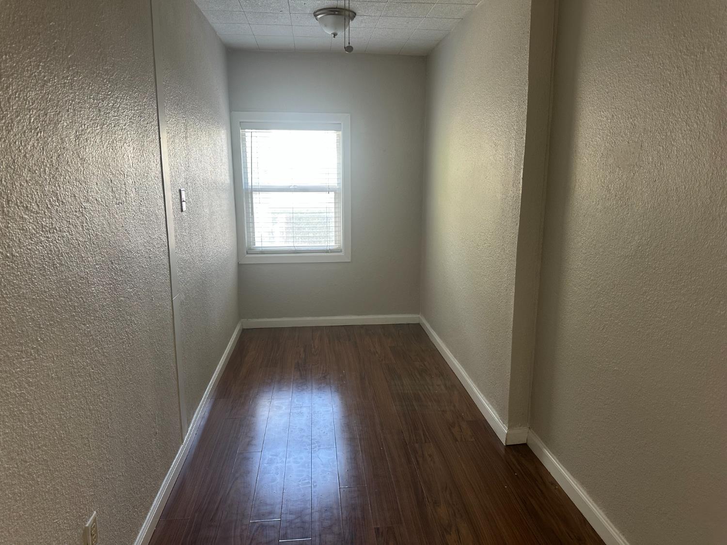 1235 N Street Newman, CA 95360 - Photo 22 of 33 an empty room with wooden floor and windows