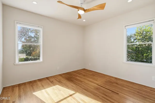 a view of empty room with wooden floor and fan