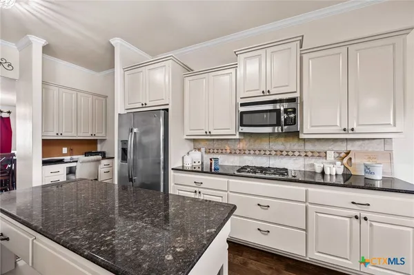 a kitchen with stainless steel appliances granite countertop a sink a stove and cabinets
