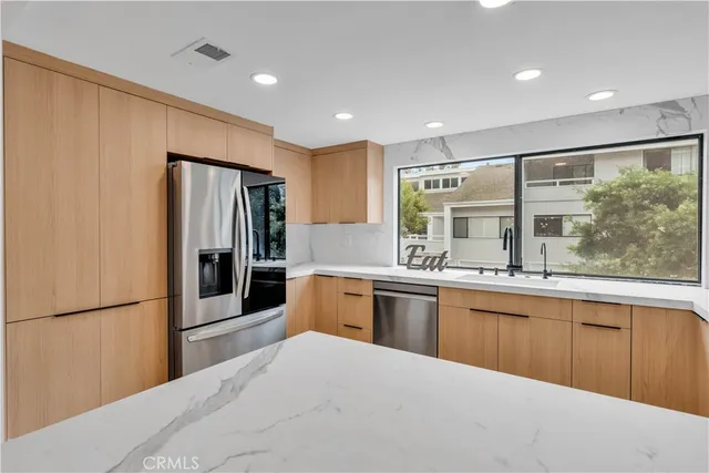 a large kitchen with stainless steel appliances granite countertop a refrigerator and a sink