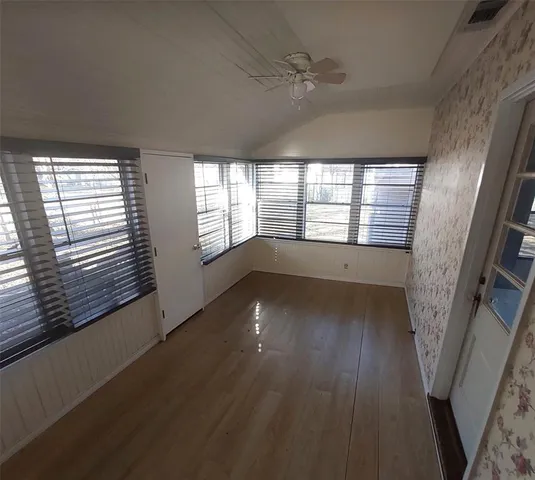a view of empty room with wooden floor and fan