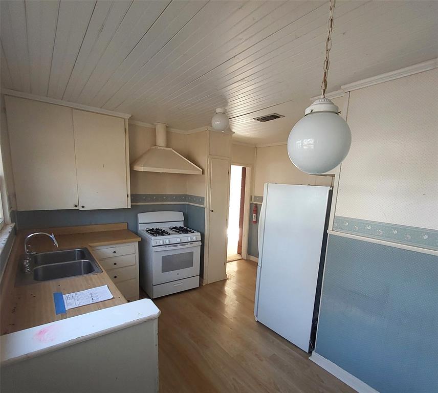 2131 Hubbard Street Paris, TX 75460 - Photo 6 of 14 a kitchen with wooden floor white cabinets and stainless steel appliances