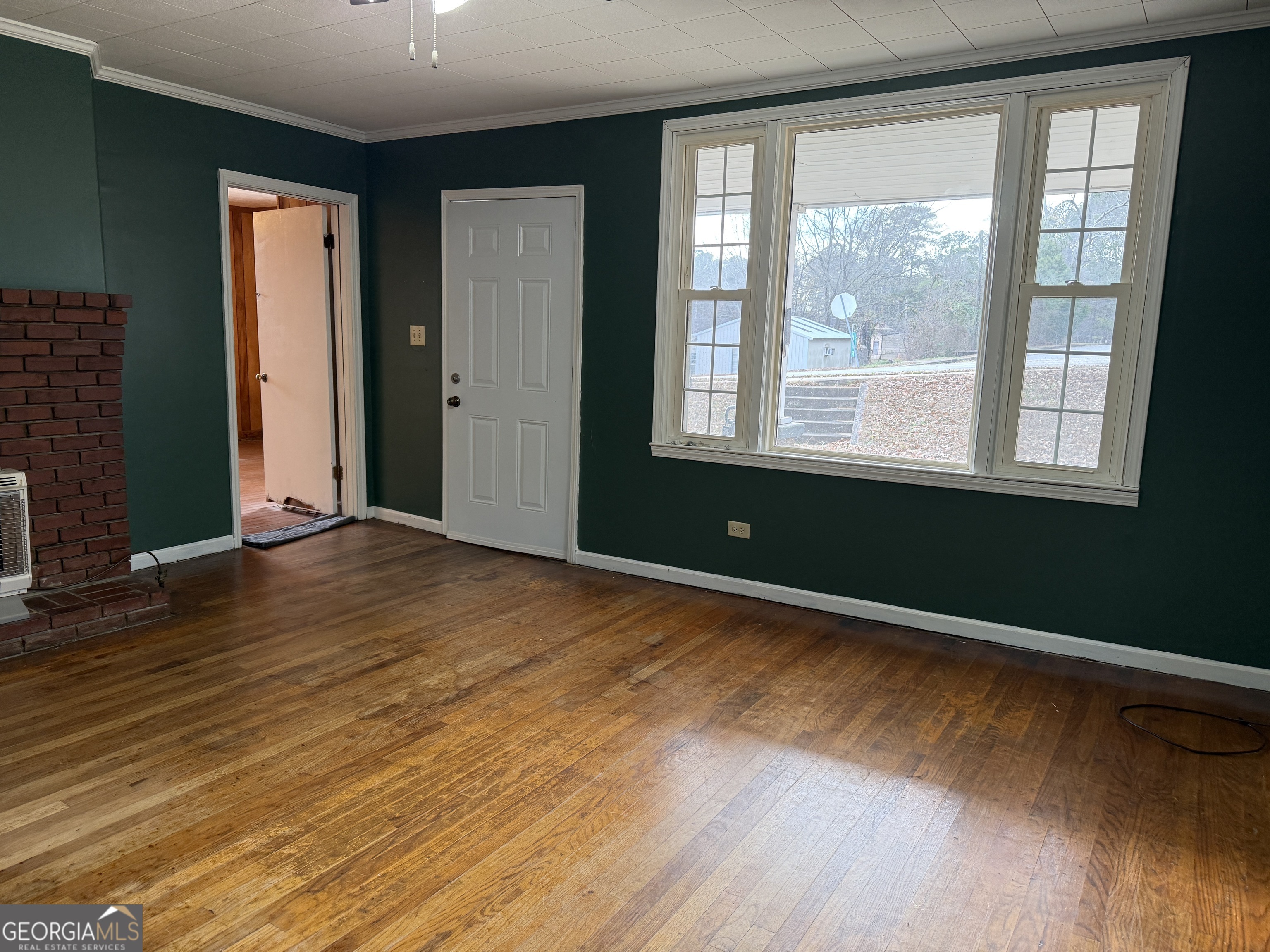 19 Truitt Street Manchester, GA 31816 - Photo 2 of 31 a view of an empty room with wooden floor and a window