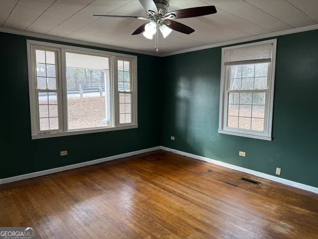 a view of empty room with wooden floor and fan