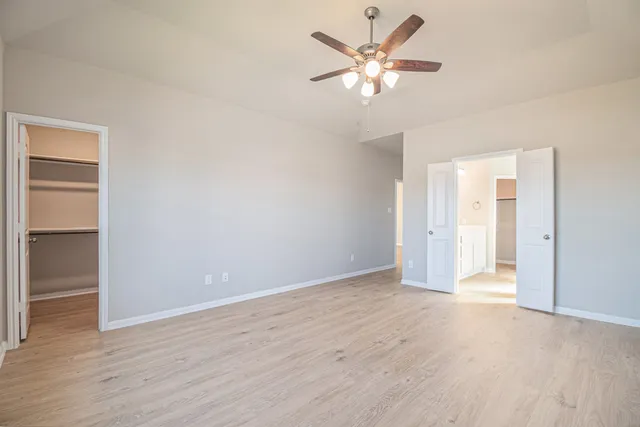 an empty room with wooden floor and ceiling fan