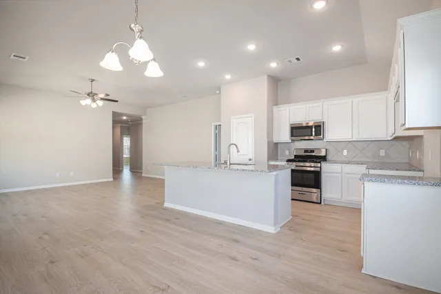 a large kitchen with cabinets wooden floor and stainless steel appliances