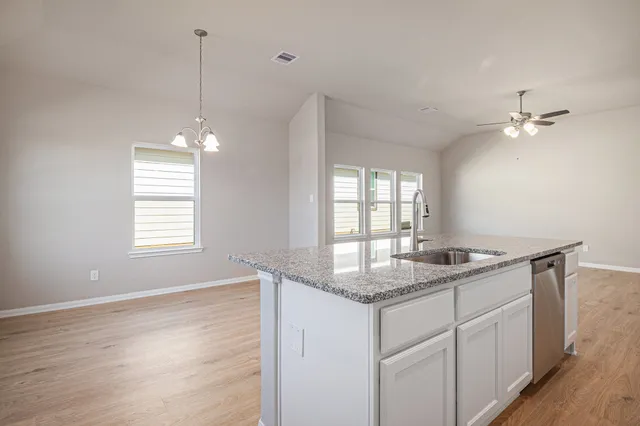a kitchen with a sink chandelier and wooden floor
