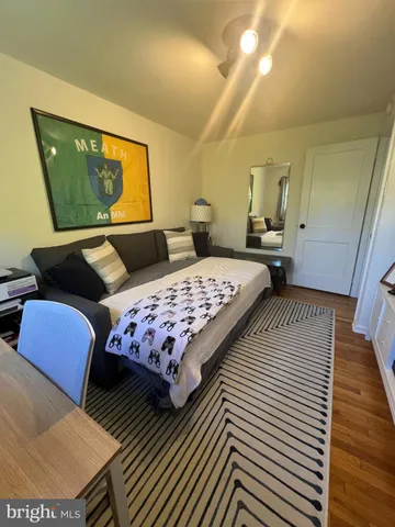 a bedroom with a bed a couch and wooden floor