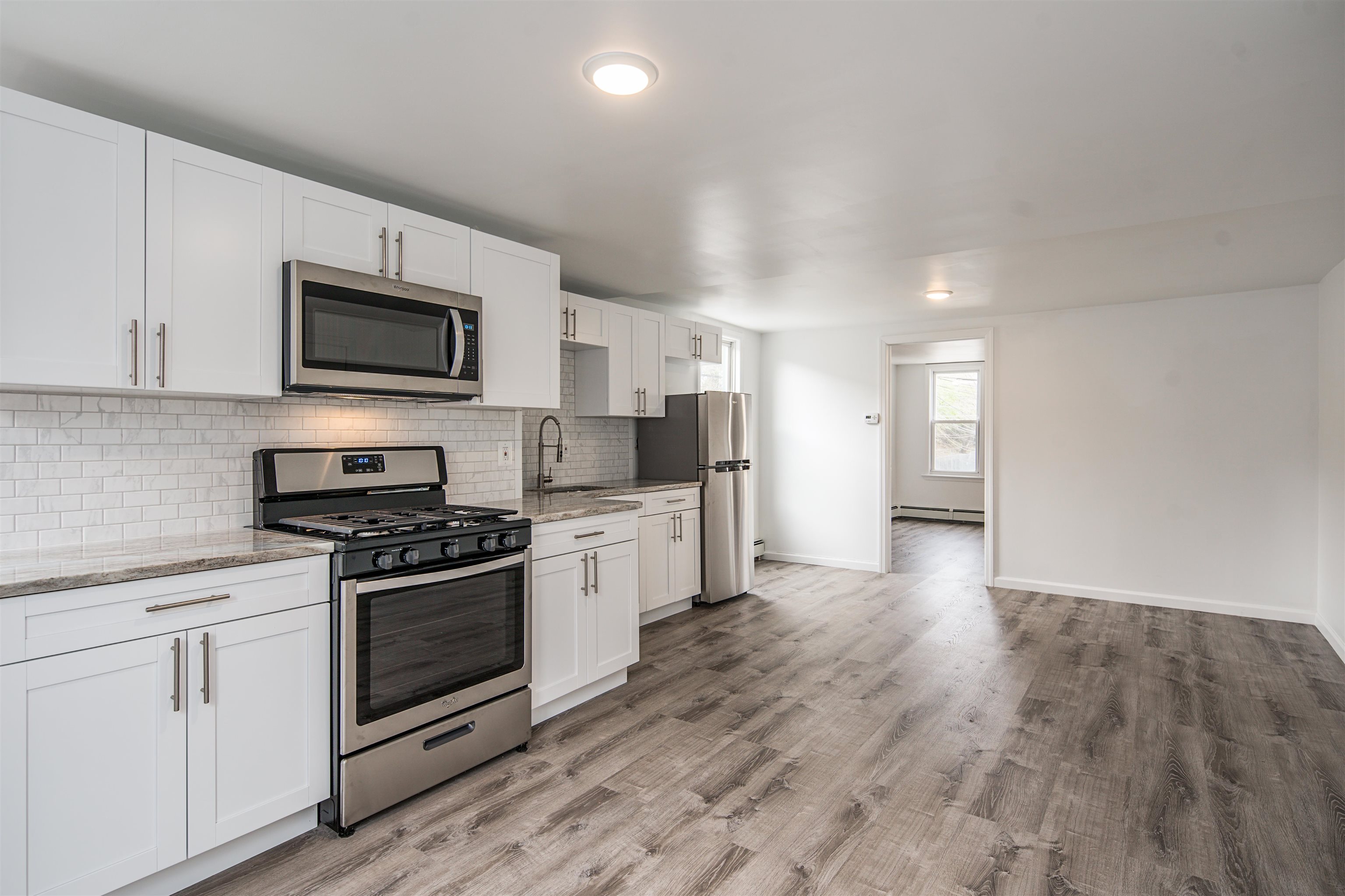 74 Colgate Street, Unit 2 Jersey City, NJ 07302 - Photo 3 of 10 a kitchen with stainless steel appliances granite countertop a stove top oven a sink dishwasher and a refrigerator with wooden floor
