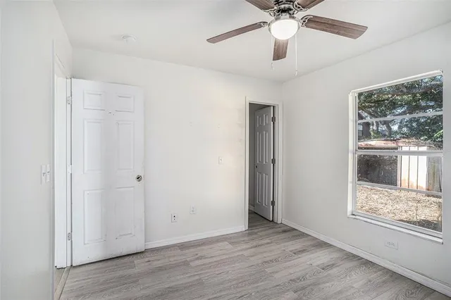 a view of an empty room with a window and wooden floor