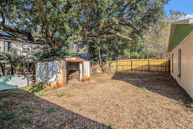 a view of a backyard with wooden fence and large trees