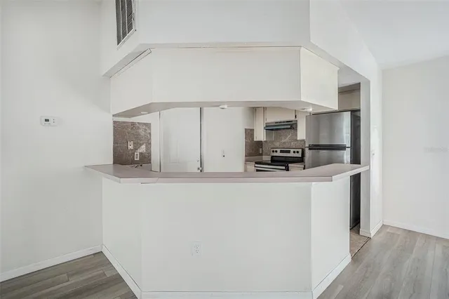 a view of kitchen with stainless steel appliances wooden floor
