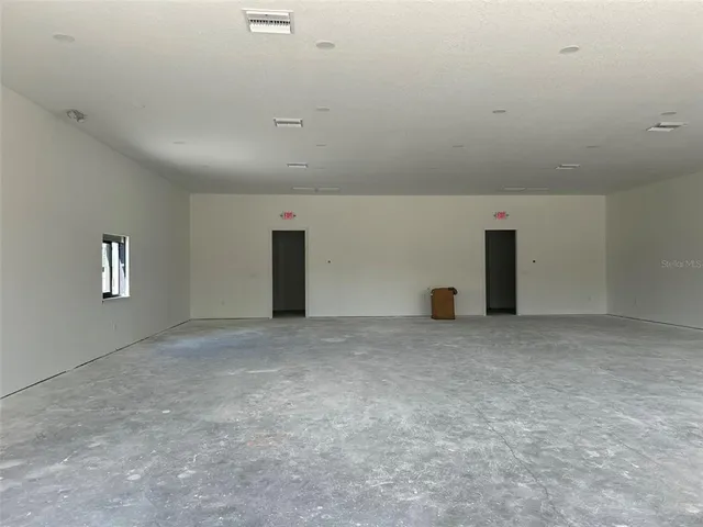 an empty room with windows and ceiling fan