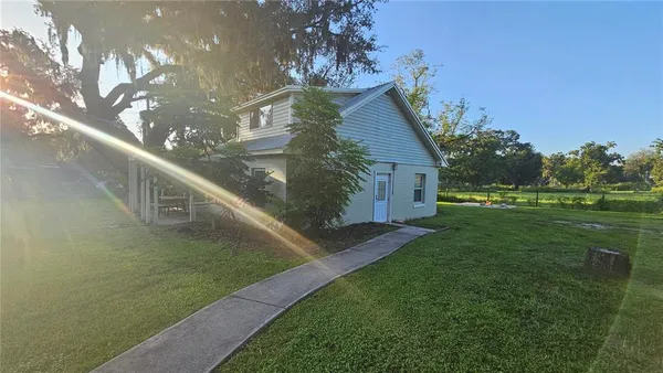 a view of a house in a big yard with large trees