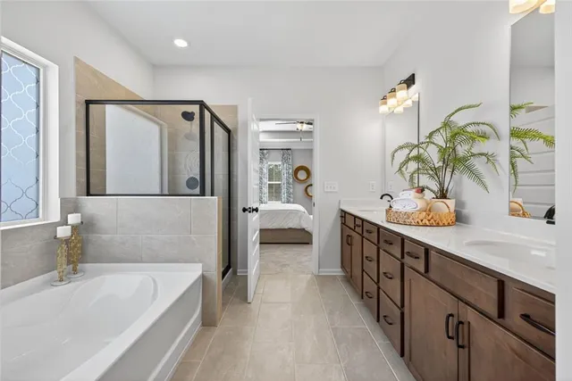 a spacious en suite bathroom with a double vanity sink tub and mirror