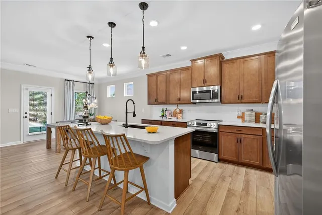 a kitchen with stainless steel appliances granite countertop a stove top oven a sink dishwasher a dining table and chairs with wooden floor