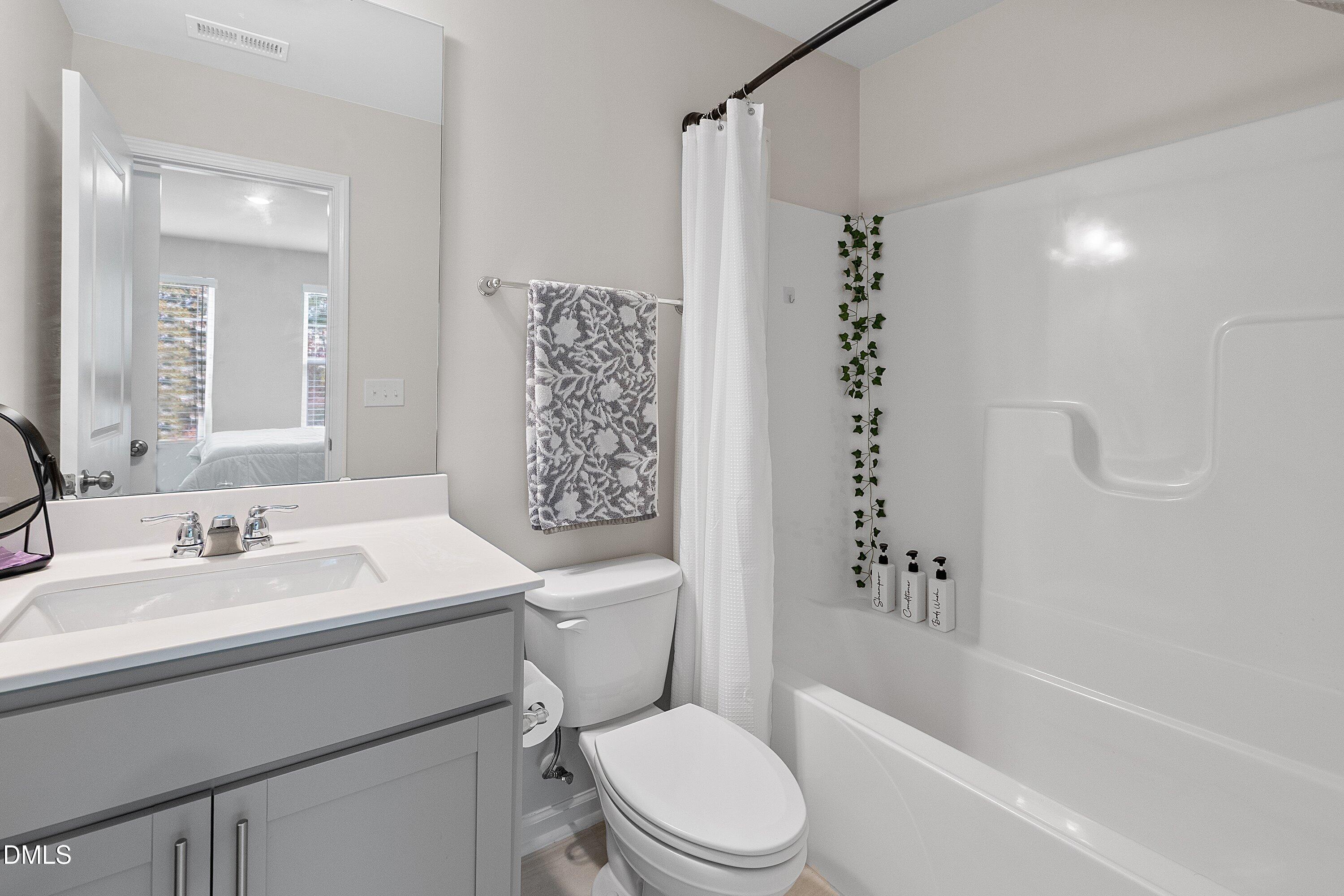 4949 Microcline Trail Raleigh, NC 27610 - Photo 15 of 42 a bathroom with a sink a toilet a mirror a vanity and shower
