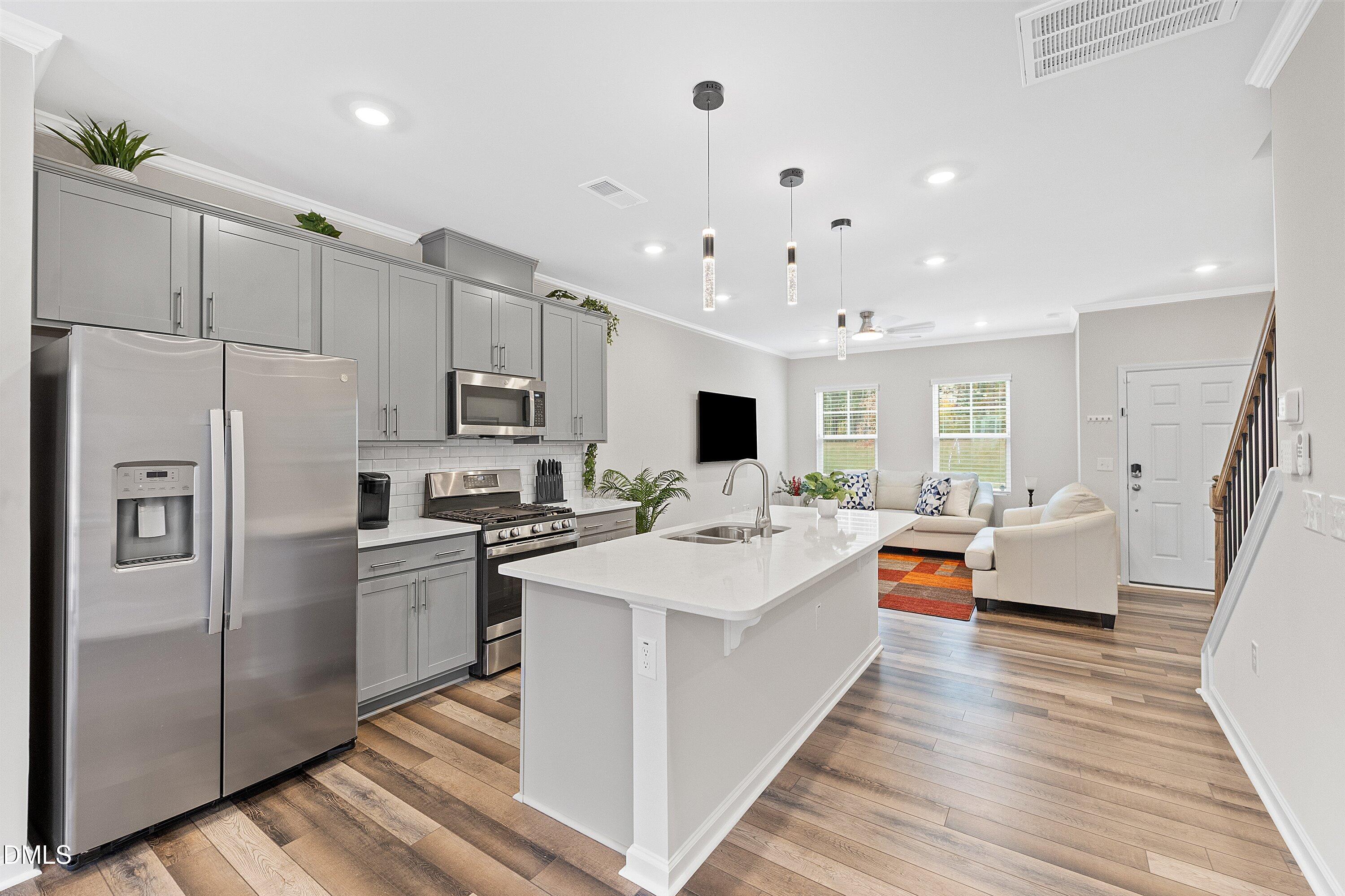 4949 Microcline Trail Raleigh, NC 27610 - Photo 2 of 42 a large white kitchen with a refrigerator a stove top oven a sink dishwasher and white cabinets with wooden floor