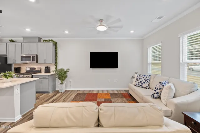 a large white kitchen with a refrigerator a stove top oven a sink dishwasher and white cabinets with wooden floor