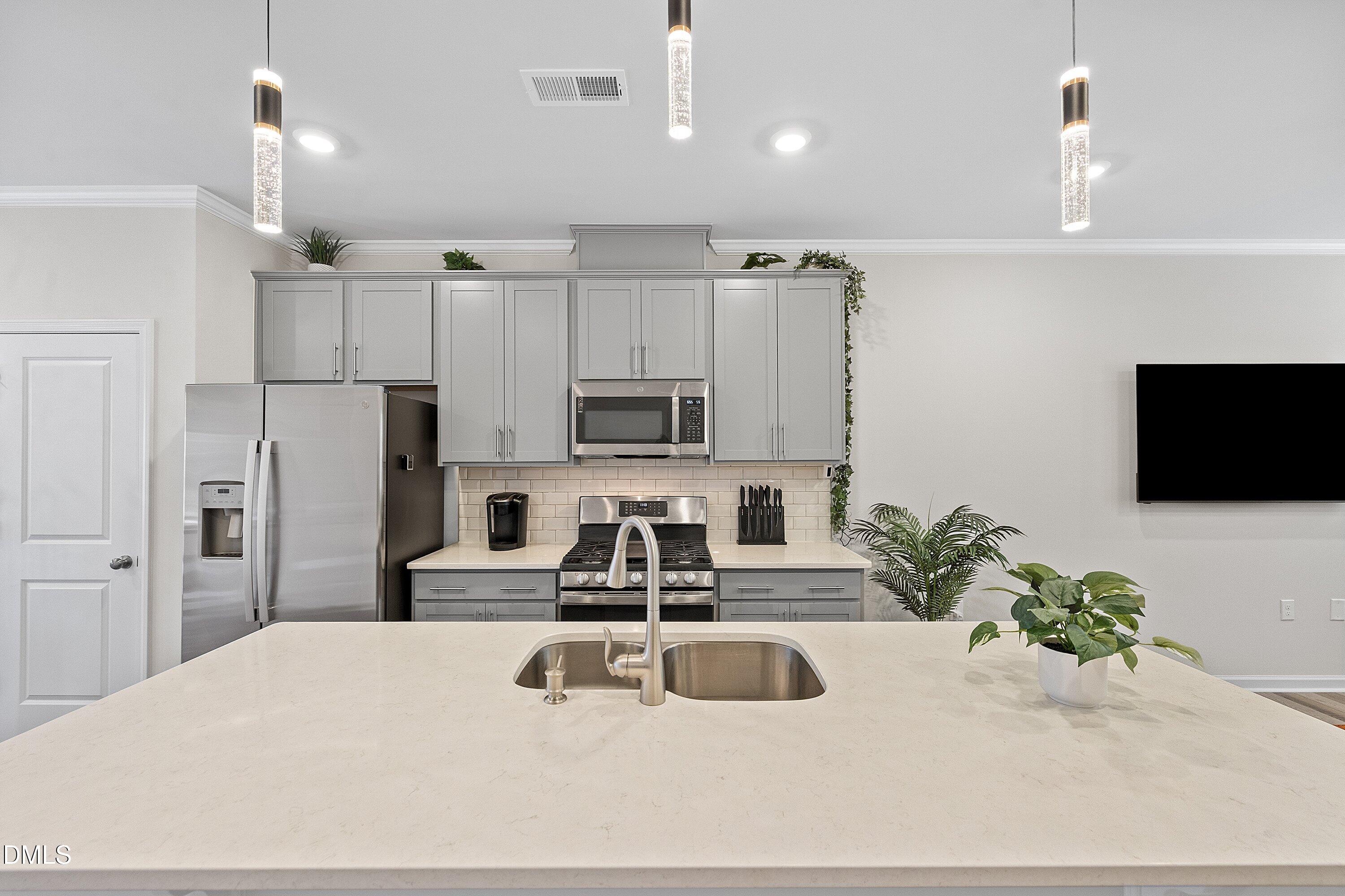 4949 Microcline Trail Raleigh, NC 27610 - Photo 7 of 42 a kitchen with stainless steel appliances a sink a refrigerator a microwave a stove and white cabinets with wooden floor