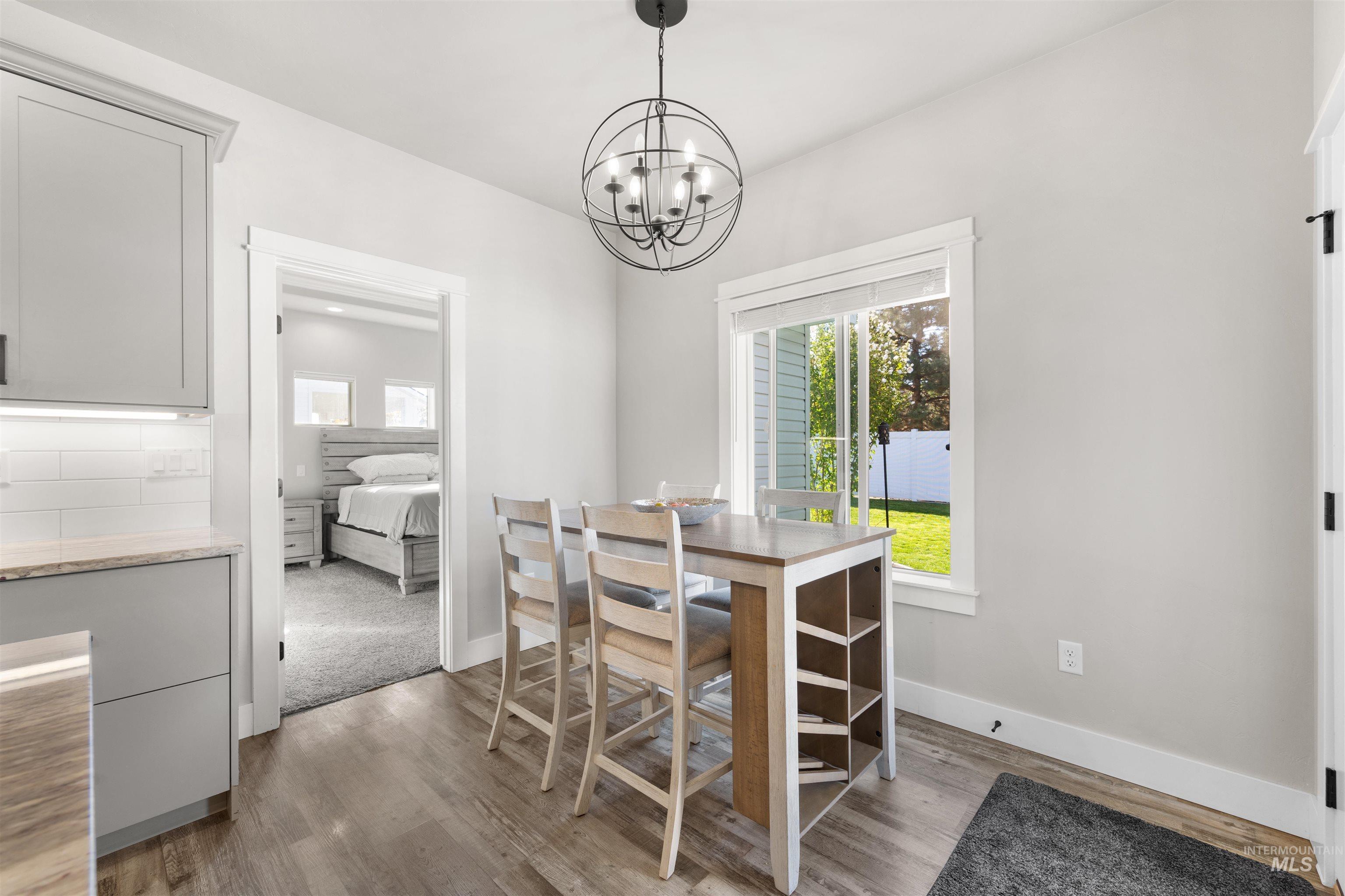 2958 Sunlight Road Twin Falls, ID 83301 - Photo 16 of 40 Wood-finish flooring, light grey cabinetry, white subway tile backsplash, and a modern orb chandelier