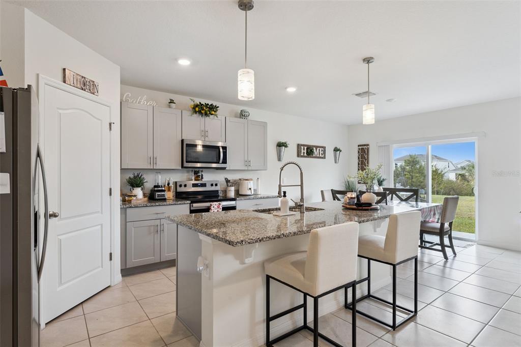 1502 Bitteroot Street Kissimmee, FL 34744 - Photo 7 of 29 a kitchen with stainless steel appliances granite countertop a refrigerator a sink dishwasher a stove and white cabinets with wooden floor