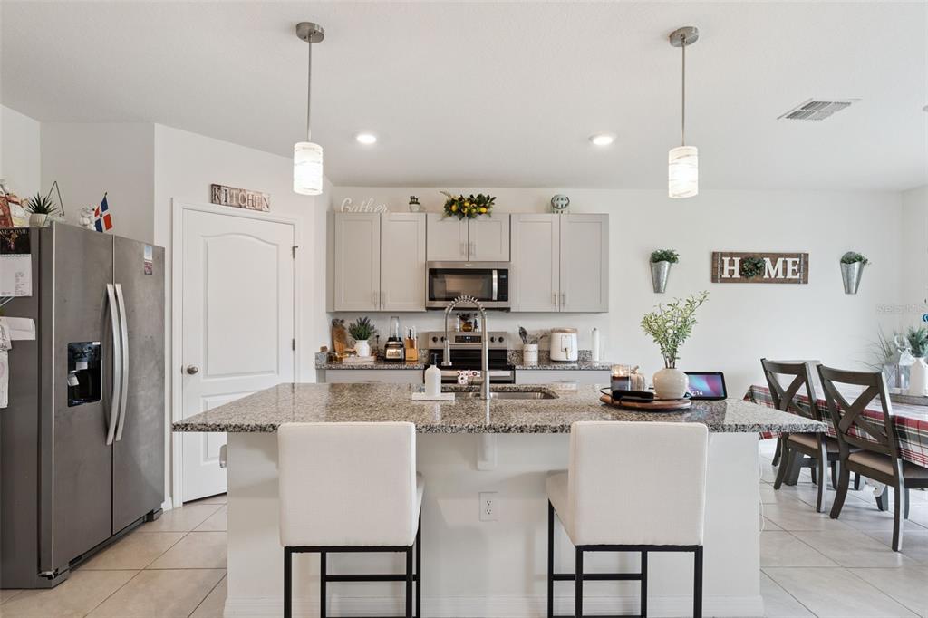 1502 Bitteroot Street Kissimmee, FL 34744 - Photo 9 of 29 a kitchen with kitchen island granite countertop a refrigerator a stove a kitchen island and chairs with wooden floor