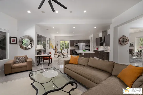 a living room with furniture kitchen view and a wooden floor