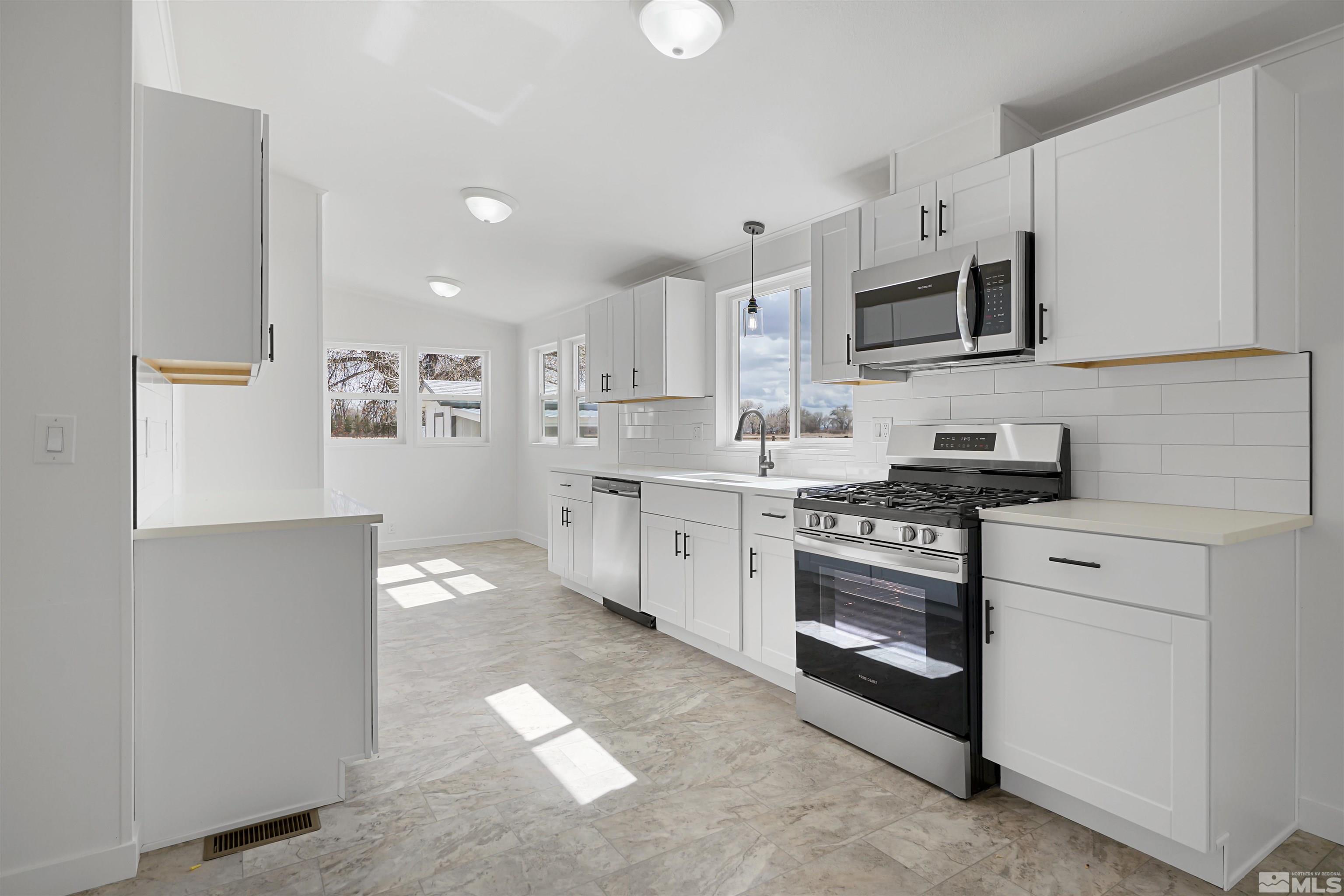 3975 Alcorn Road Fallon, NV 89406 - Photo 6 of 21 a kitchen with stainless steel appliances granite countertop white cabinets a sink a stove a microwave and a refrigerator