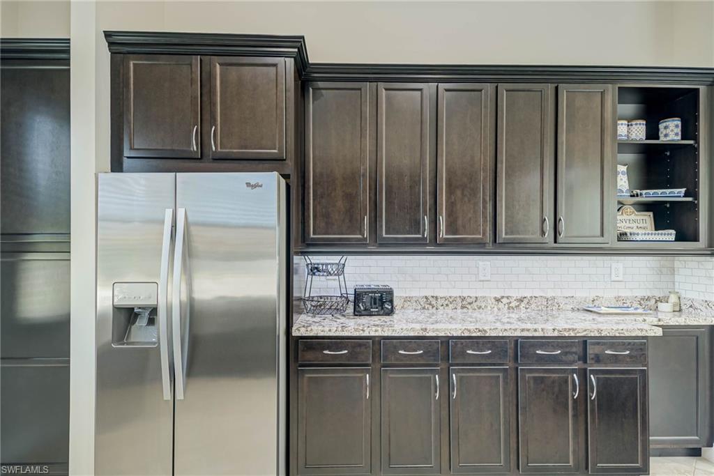 5254 Messina Street Ave Maria, FL 34142 - Photo 11 of 32 a kitchen with granite countertop a refrigerator and cabinets