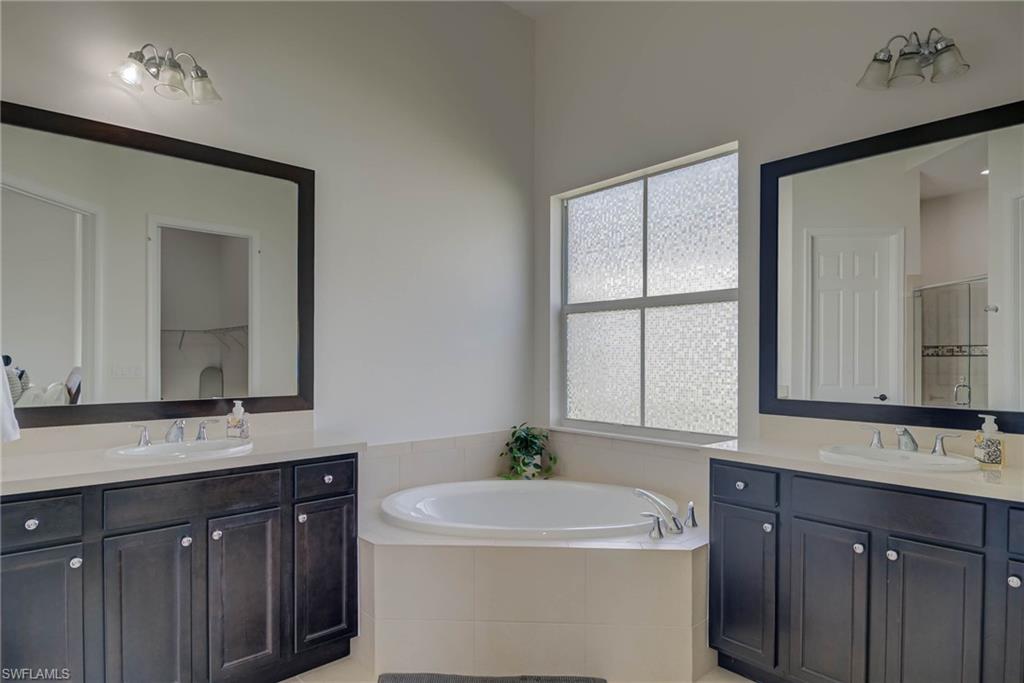 5254 Messina Street Ave Maria, FL 34142 - Photo 16 of 32 a bathroom with a double vanity sink a mirror and a bathtub