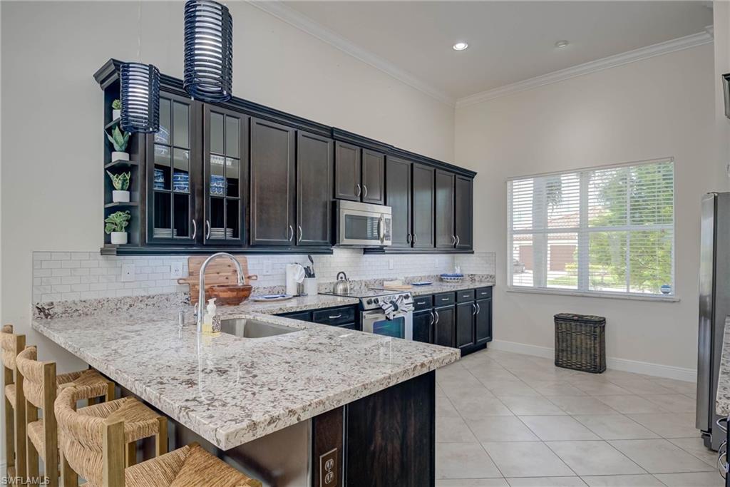 5254 Messina Street Ave Maria, FL 34142 - Photo 9 of 32 a kitchen with kitchen island granite countertop a sink and a stove