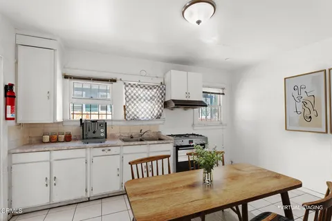 a kitchen with stainless steel appliances a table chairs in it and white cabinets
