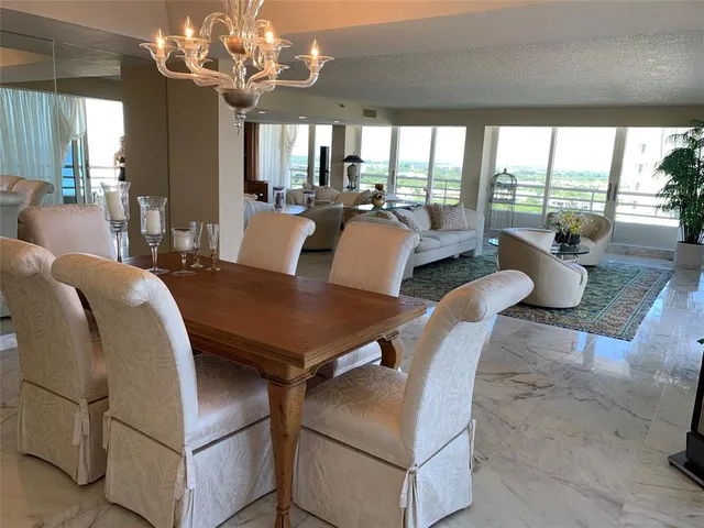 a view of a dining room with furniture a chandelier and large windows