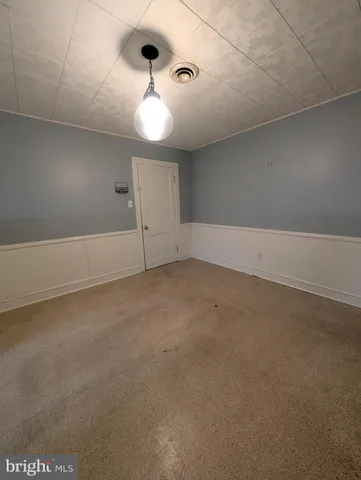 an empty room with a chandelier fan and windows