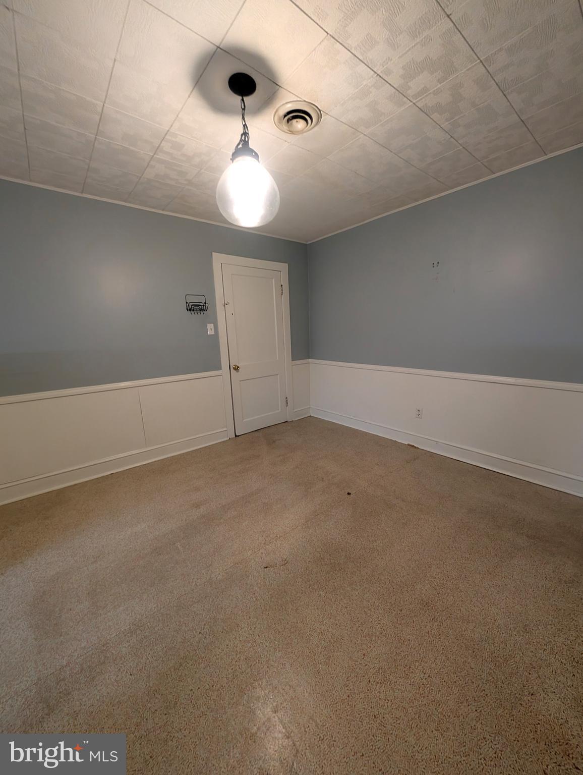 an empty room with a chandelier fan and windows